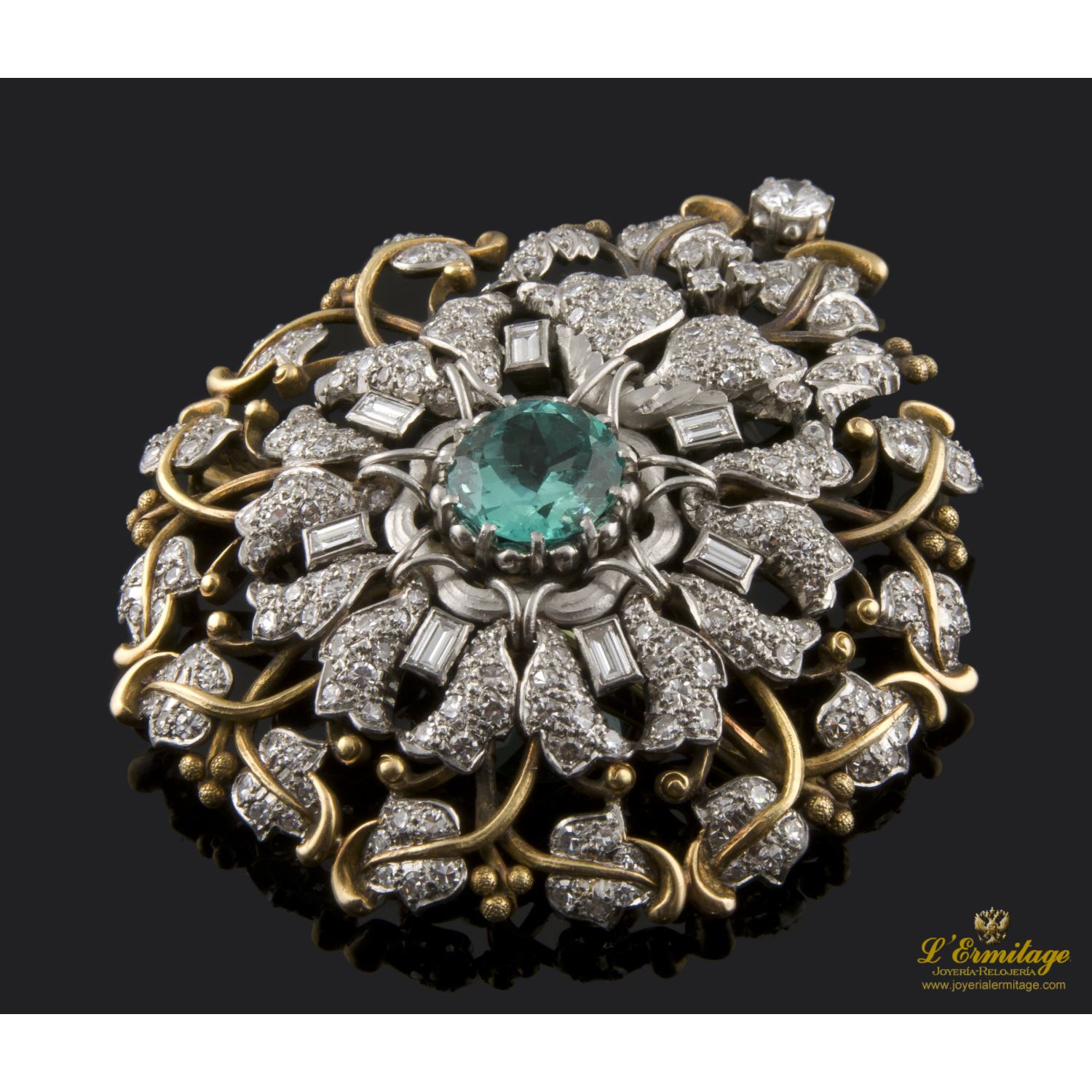 Broche realizado en oro amarillo y oro blanco. Presenta una esmeralda natural colombiana, diamantes y brillante.